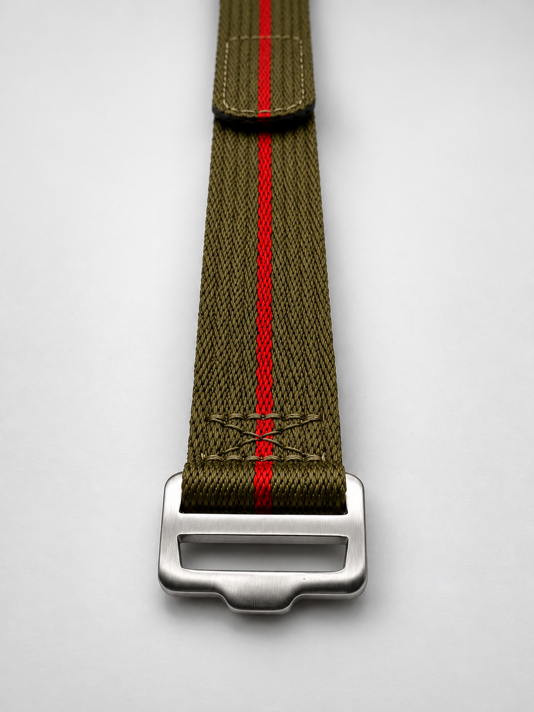 An olive green webbed watch strap with a single vibrant red center stripe and a brushed steel heavy duty buckle